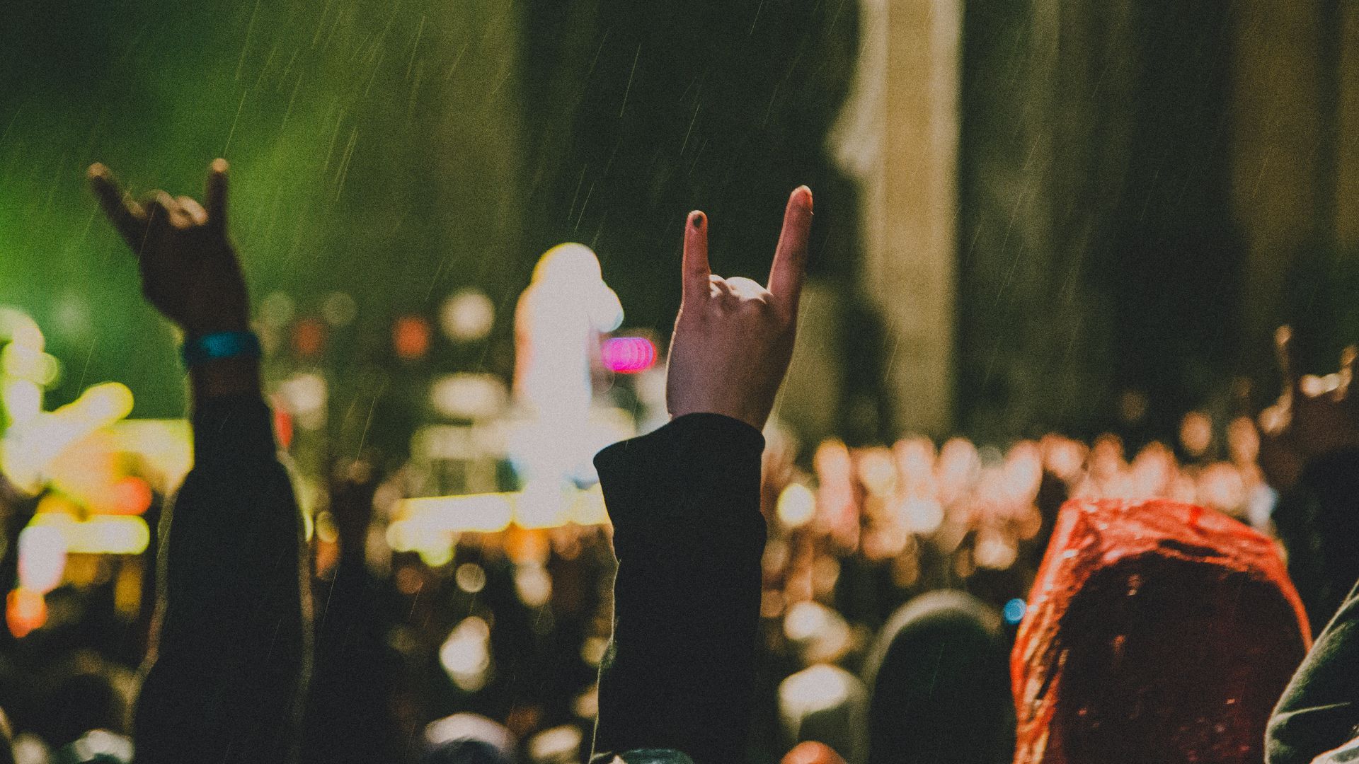 A crowd of people raising their hands in the air at a concert.