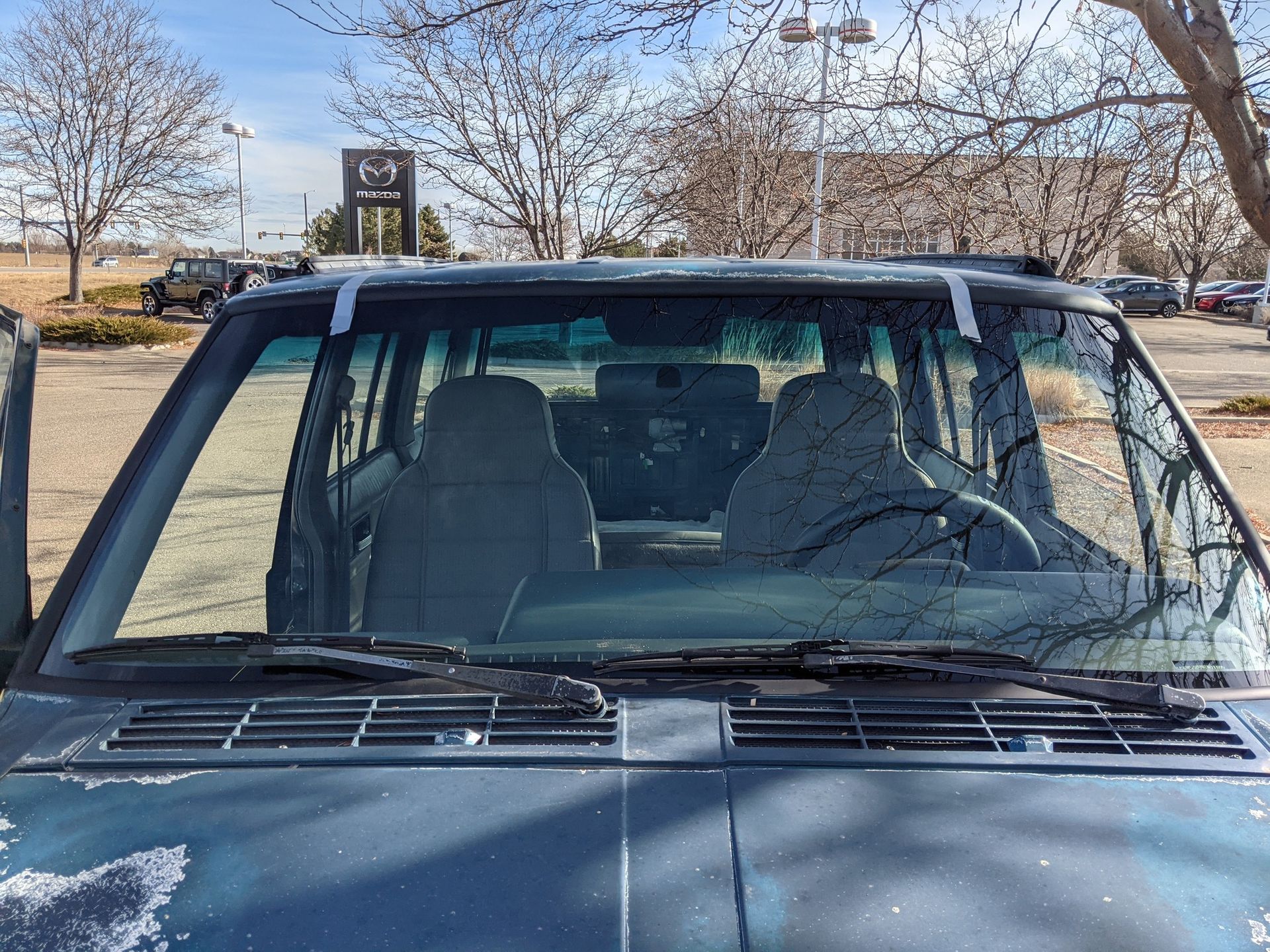 A jeep with a broken windshield is parked in a parking lot