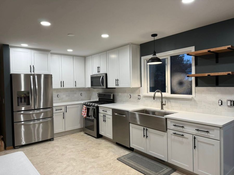A kitchen under construction with a yellow ladder in the center, featuring cream and dark brown cabinetry.
