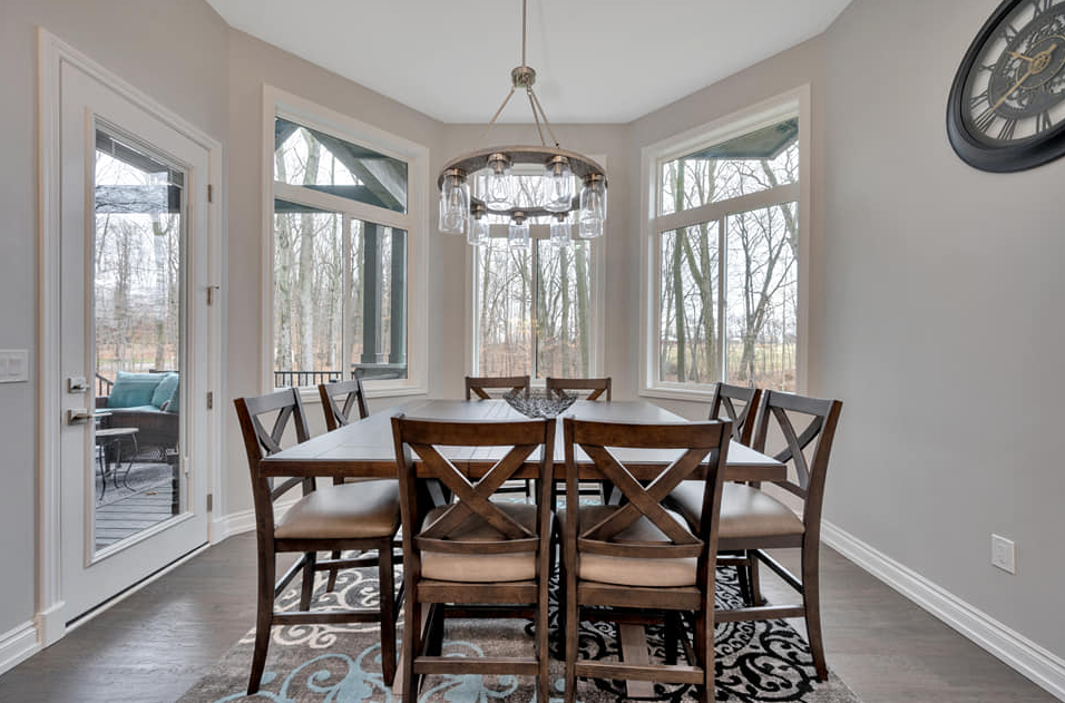 A dining room addition with a table and chairs and a clock on the wall
