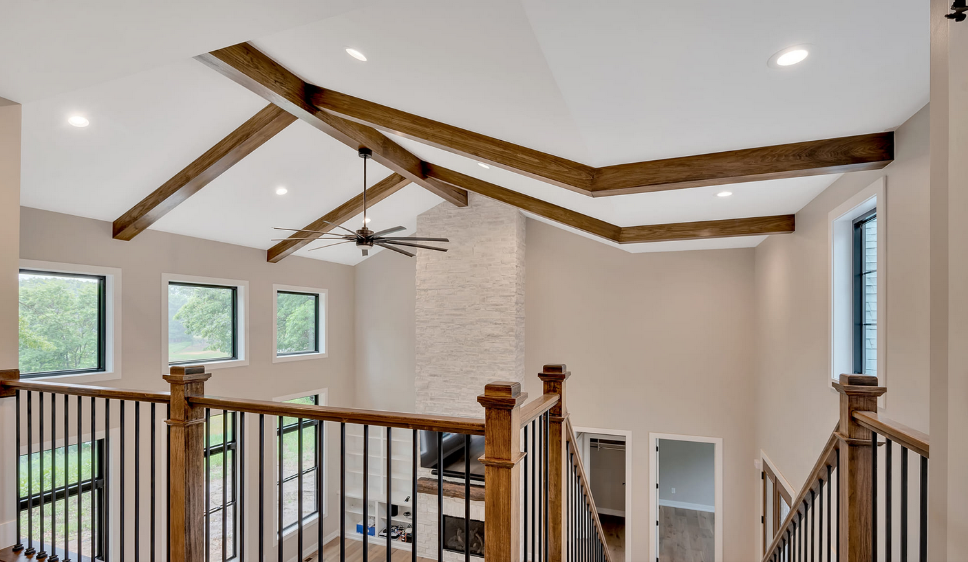 A staircase with wooden ceiling beams and a ceiling fan