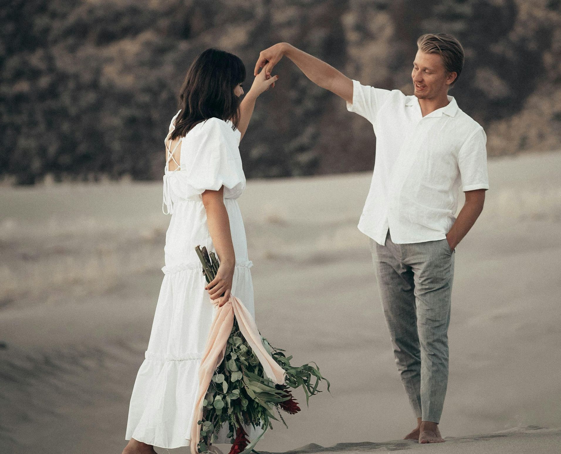 woman and man dancing in the sand
