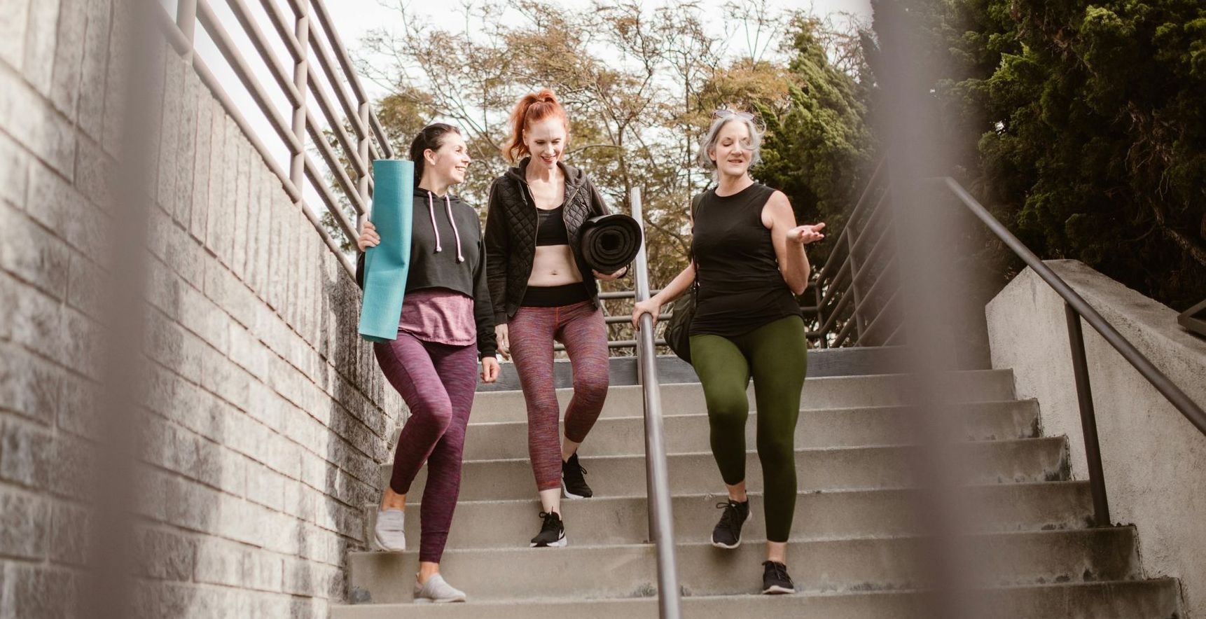 3 women walking down to stairs after exercise class talking about perimenopause