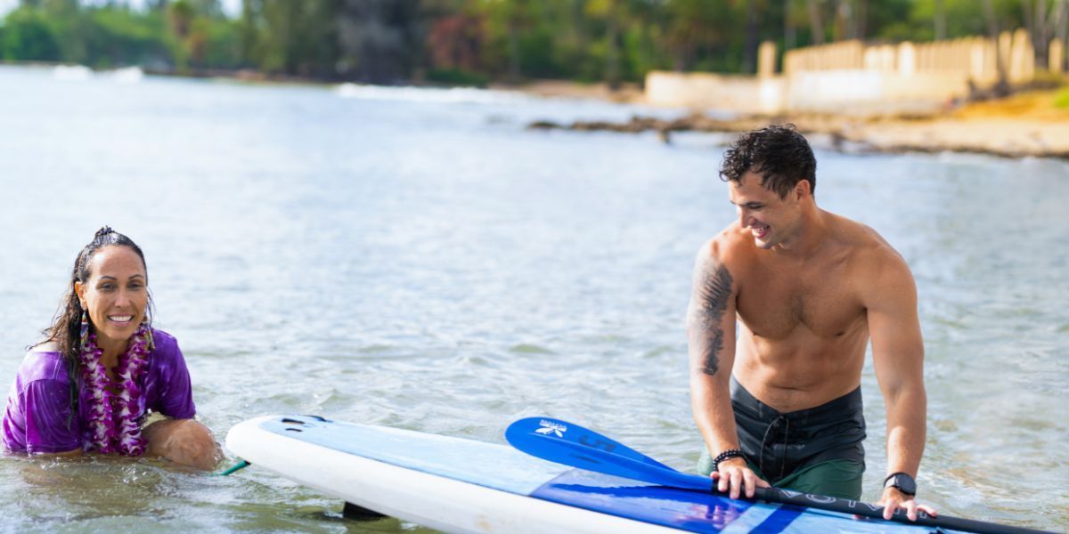 Staff helps a guest at our Hawaii couples intimacy therapy retreat use  a surfboard. 