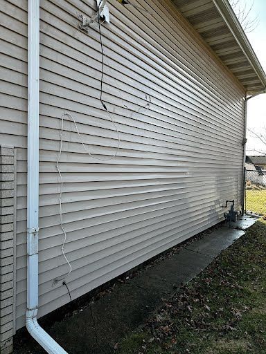 A white house with a white gutter on the side of it.