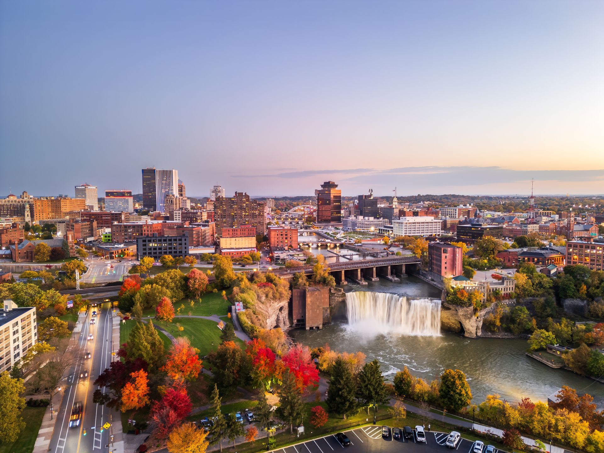 Cityscape with a waterfall and autumn trees; Rochester, NY. Buildings, sky, water and fall foliage.