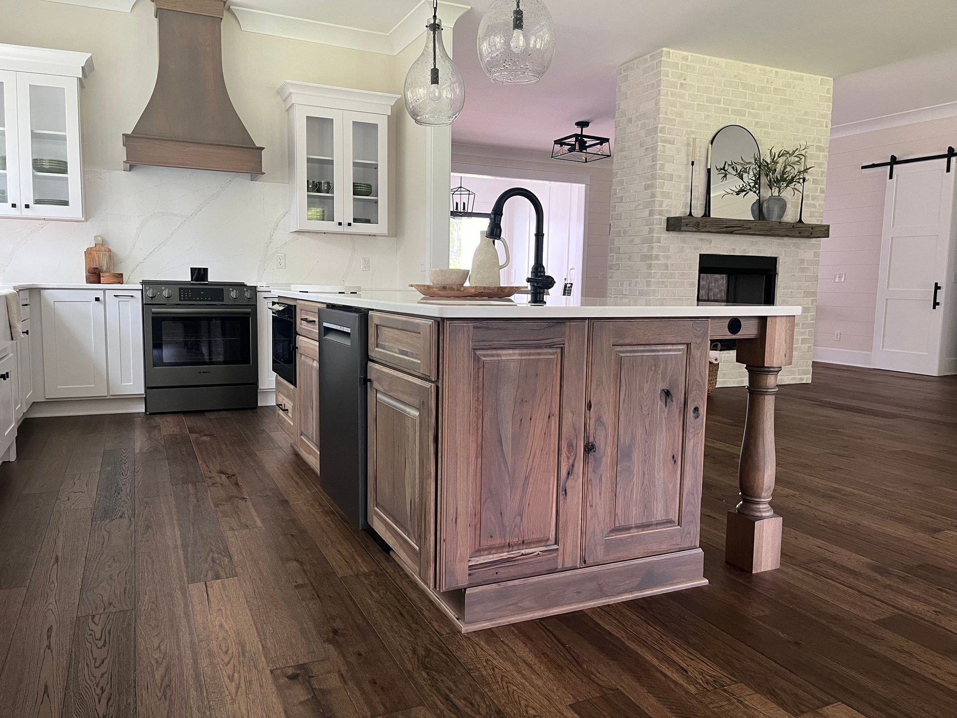 Rustic kitchen with dark wood floors, central island, white cabinets, and a range hood.