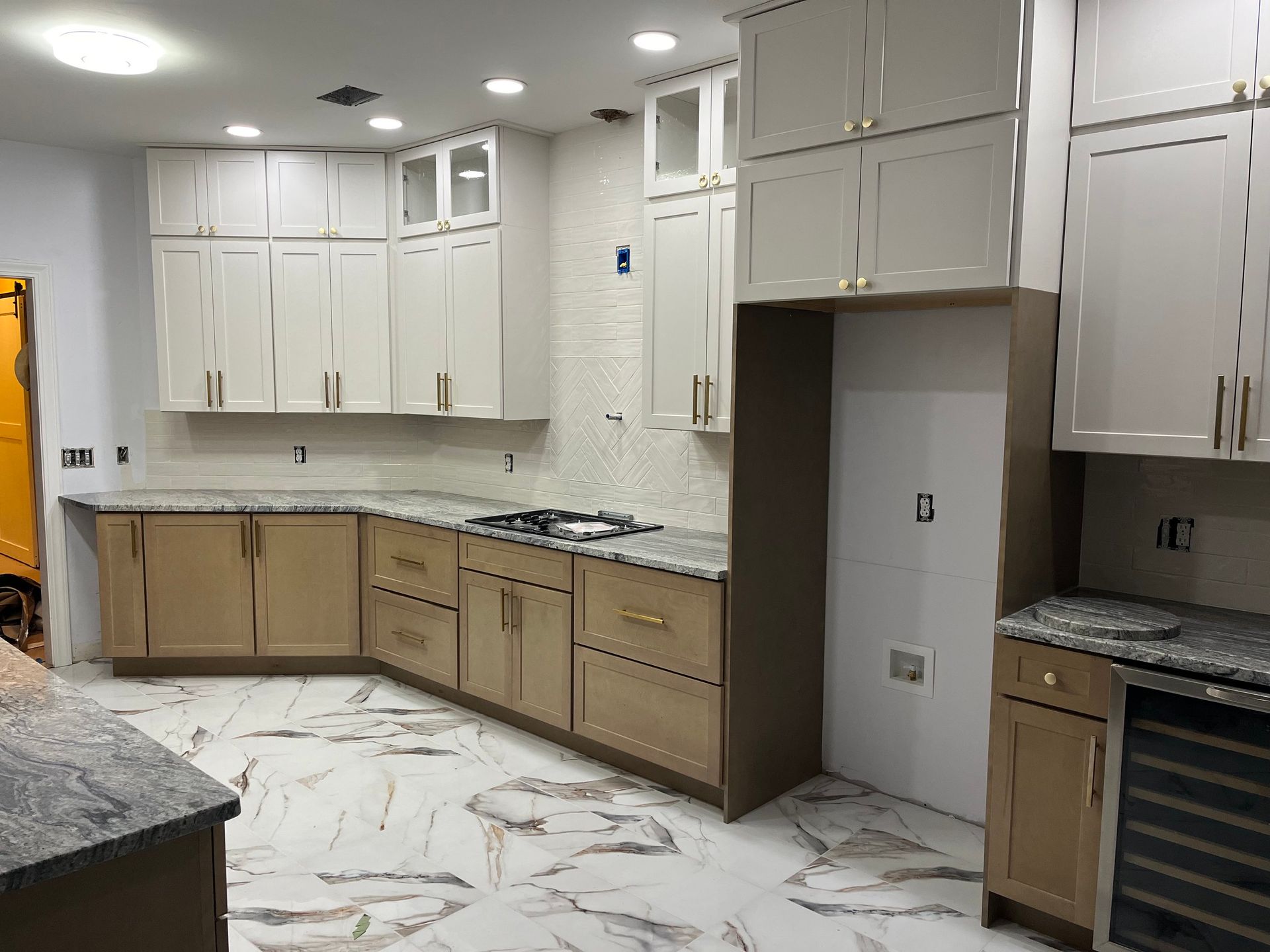 Empty kitchen with white cabinets, granite countertops, and a marble-patterned tile floor