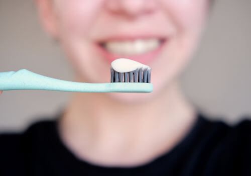 Toothbrush with toothpaste in front of a smiling mouth