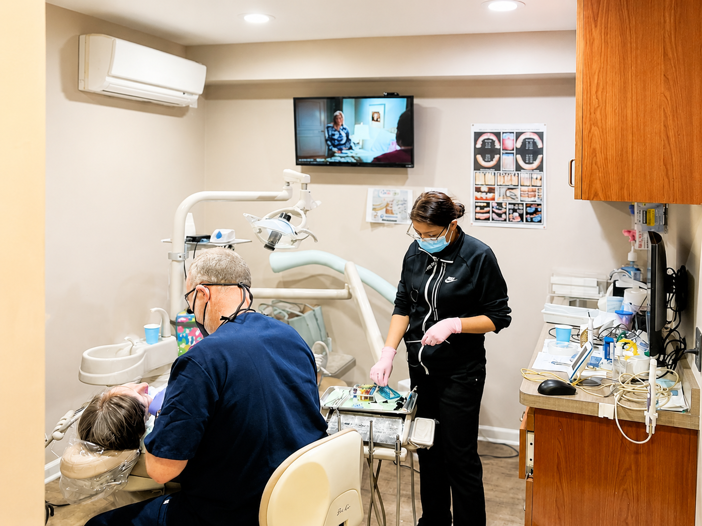 Dentist and assistant working on a patient in a small dental clinic room