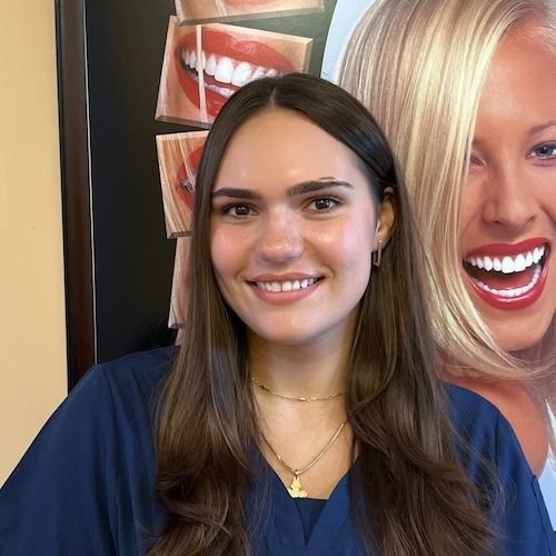 Smiling woman in a navy top standing in front of a large cosmetic poster