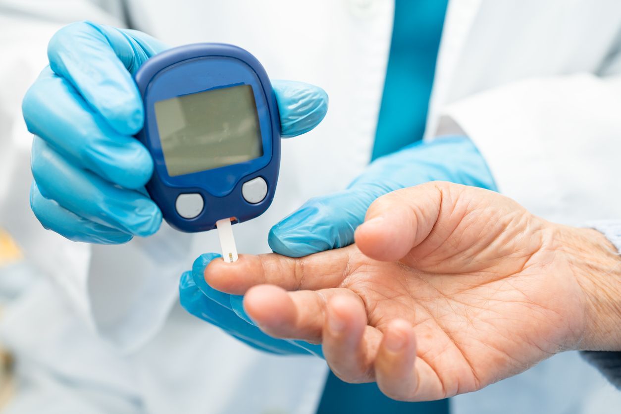 Healthcare worker checking blood sugar with a glucometer on a patient’s finger