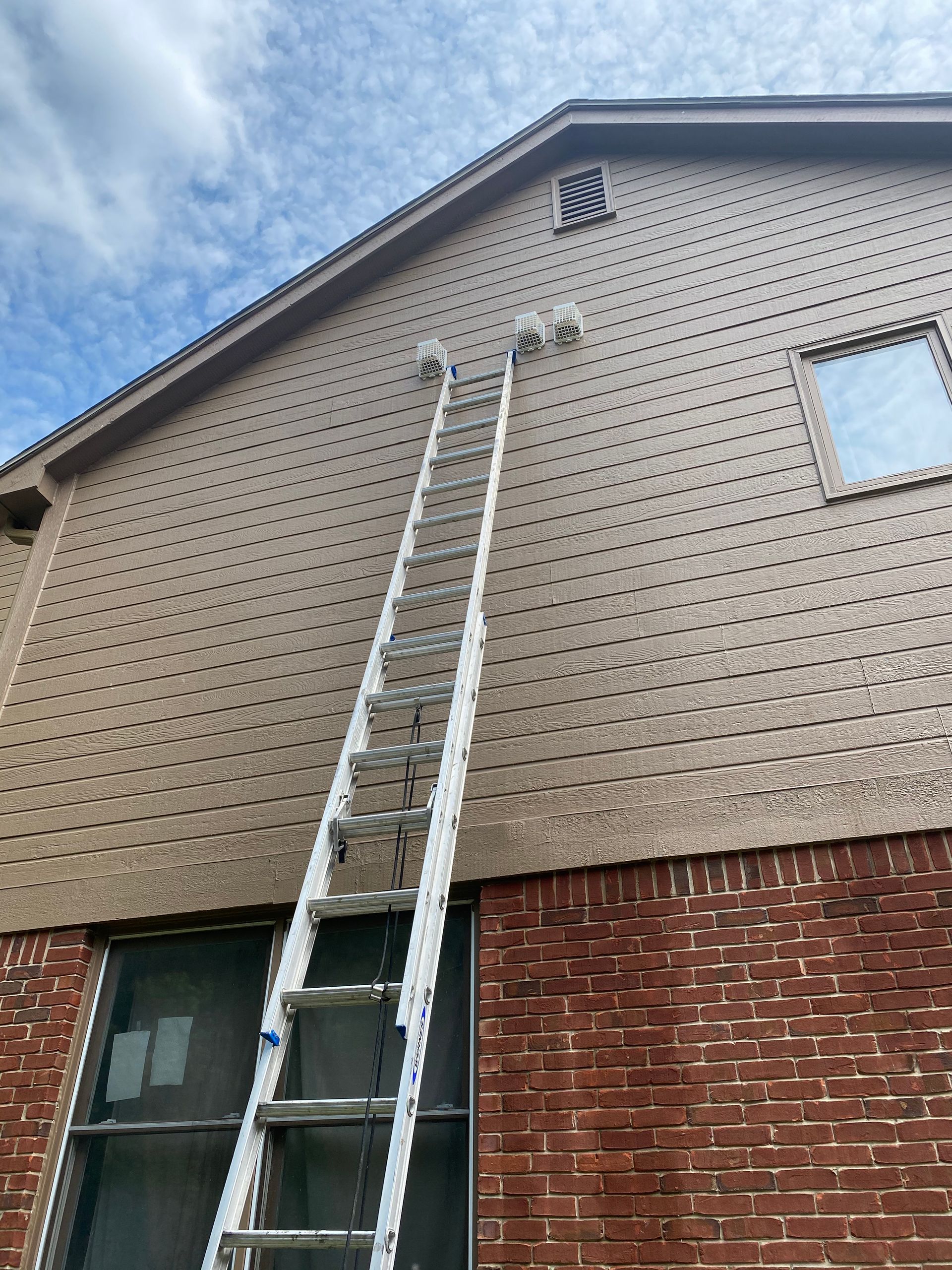 A ladder is sitting on the side of a brick building.