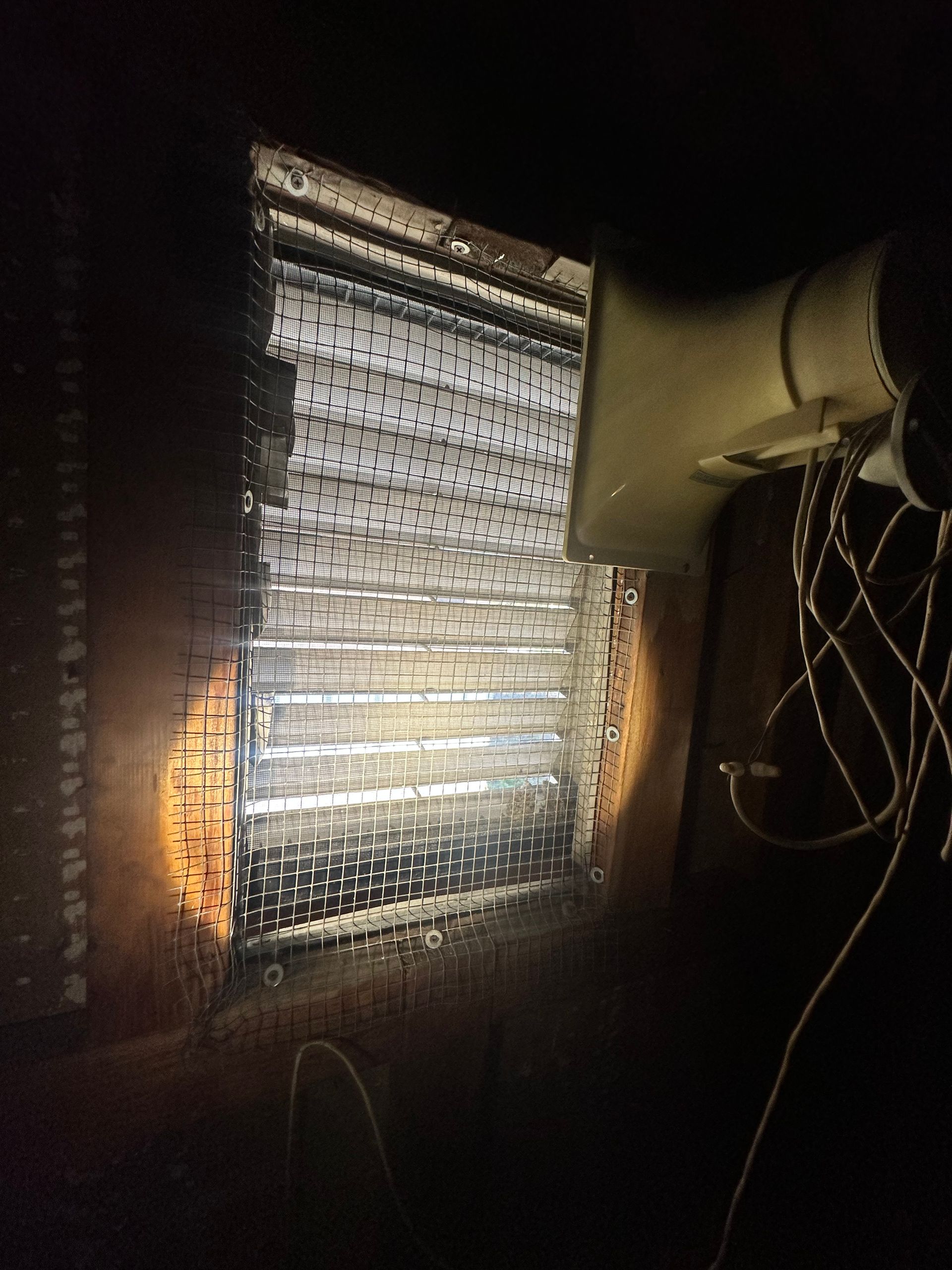 A light is shining through a hole in a wall next to a fan.