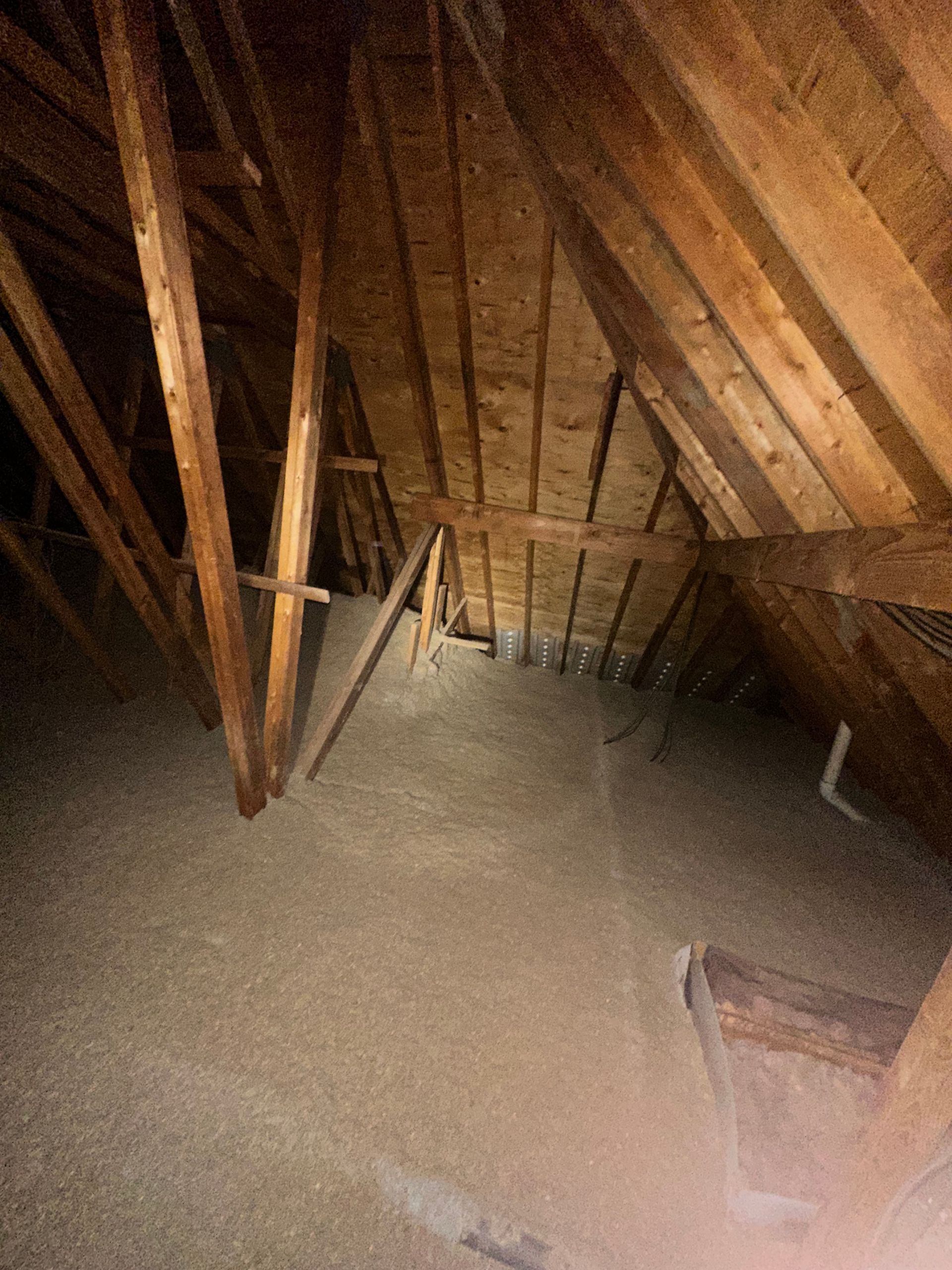 An attic with a lot of wooden beams and insulation.
