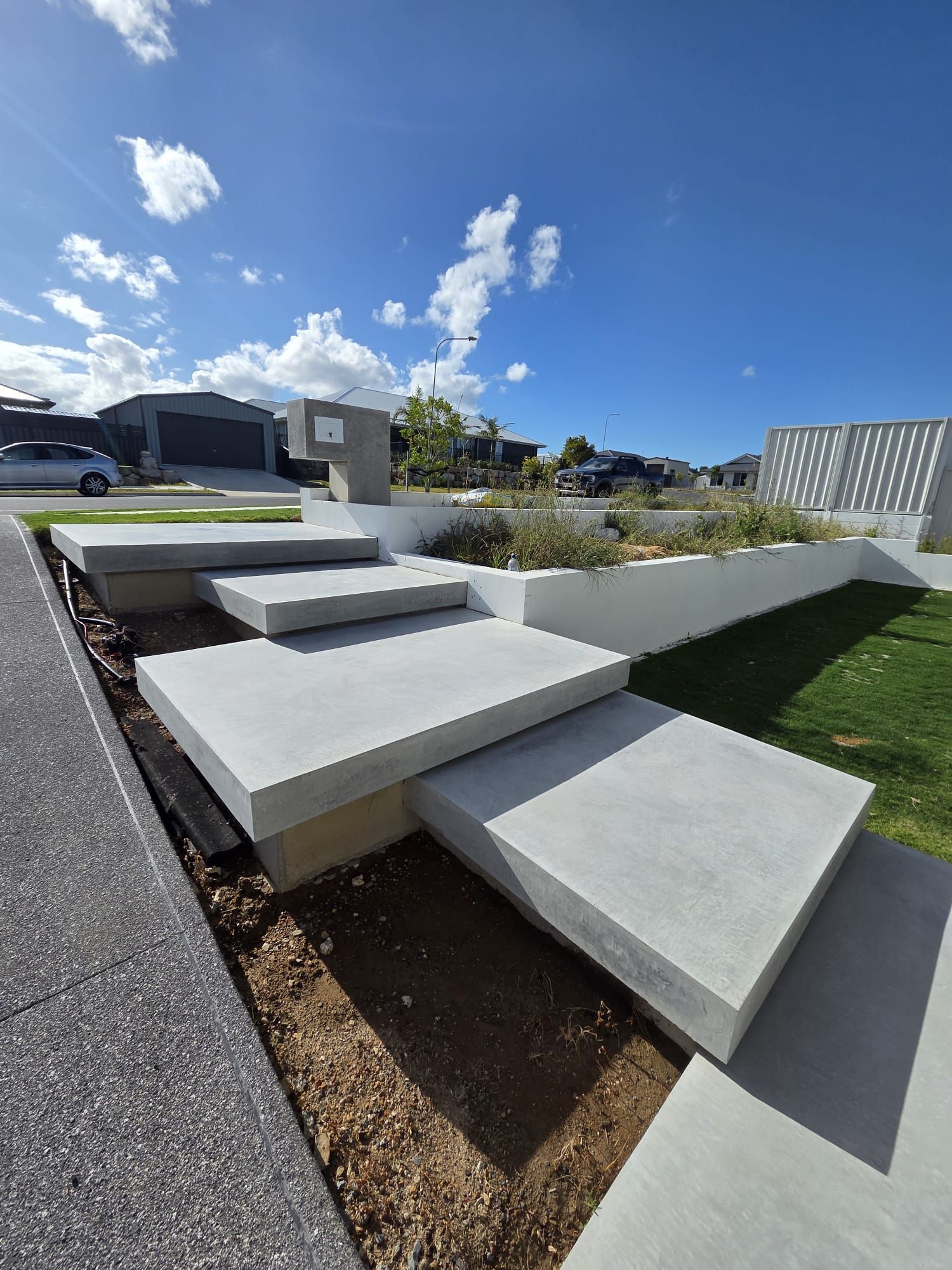 Concrete stepping stones in a modern landscaped yard under a bright blue sky. — C & A Concreting In Craignish, QLD