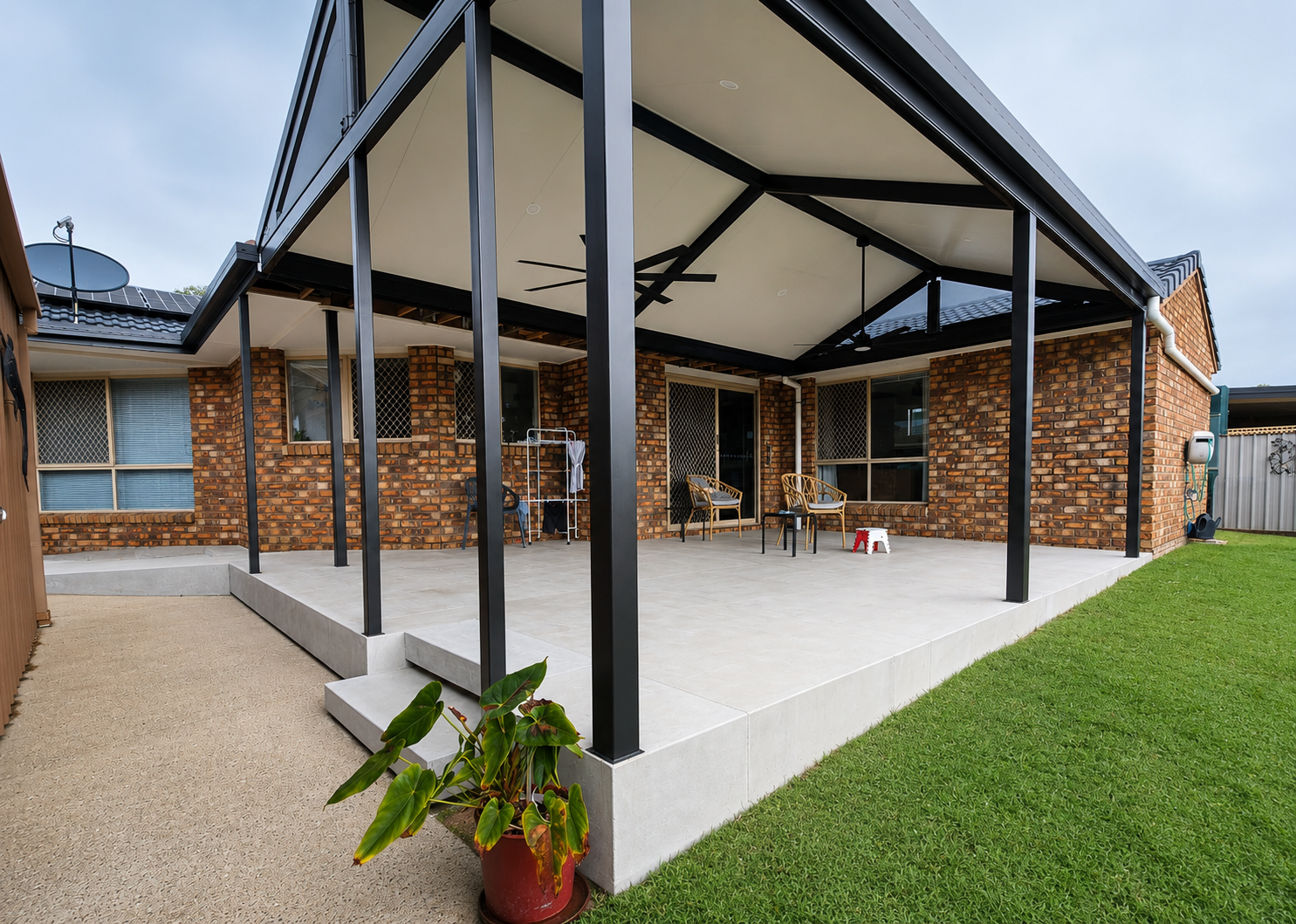Covered patio with black posts and white roof beside a brick house, overlooking a grassy yard  — C & A Concreting In Craignish, QLD