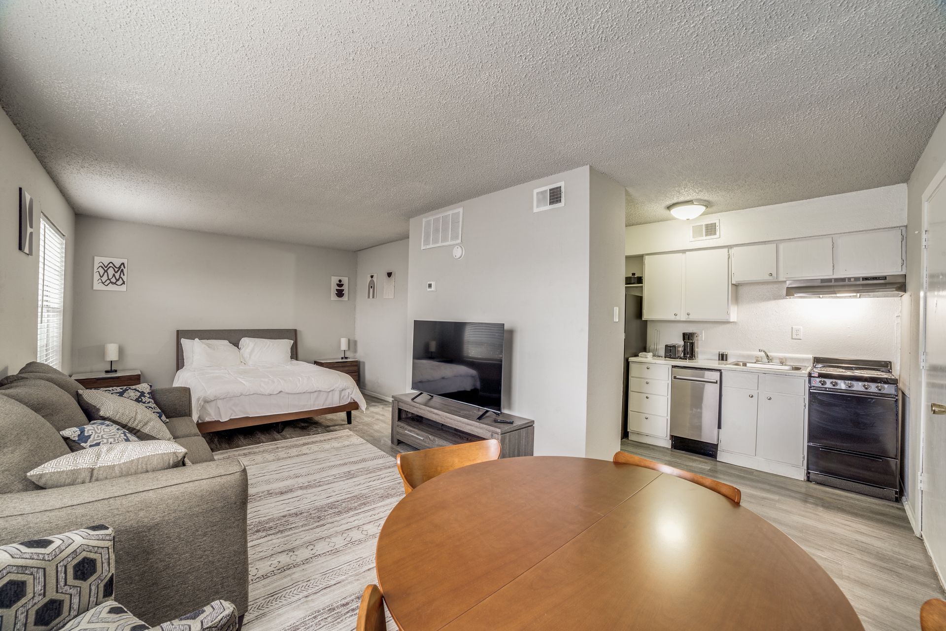 Small studio apartment with living area, bed, kitchen, couch, and TV monitor
