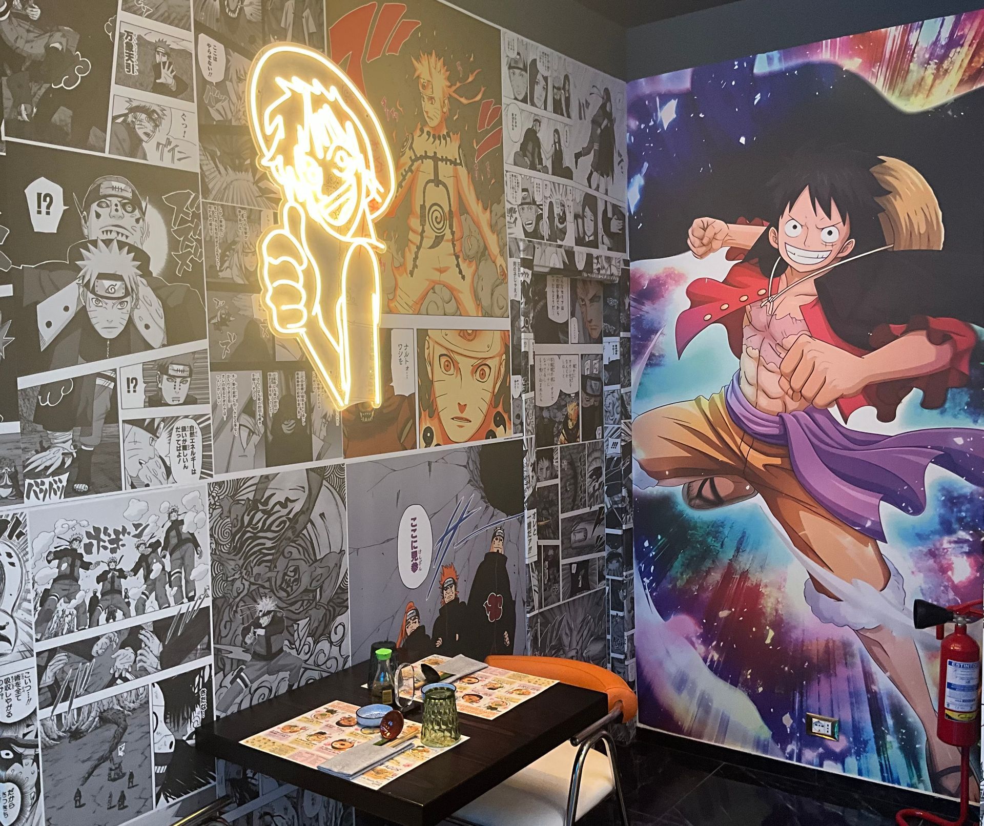 Camera a tema anime con pareti decorate con collage di manga, insegna al neon e un grande murale colorato raffigurante un personaggio.