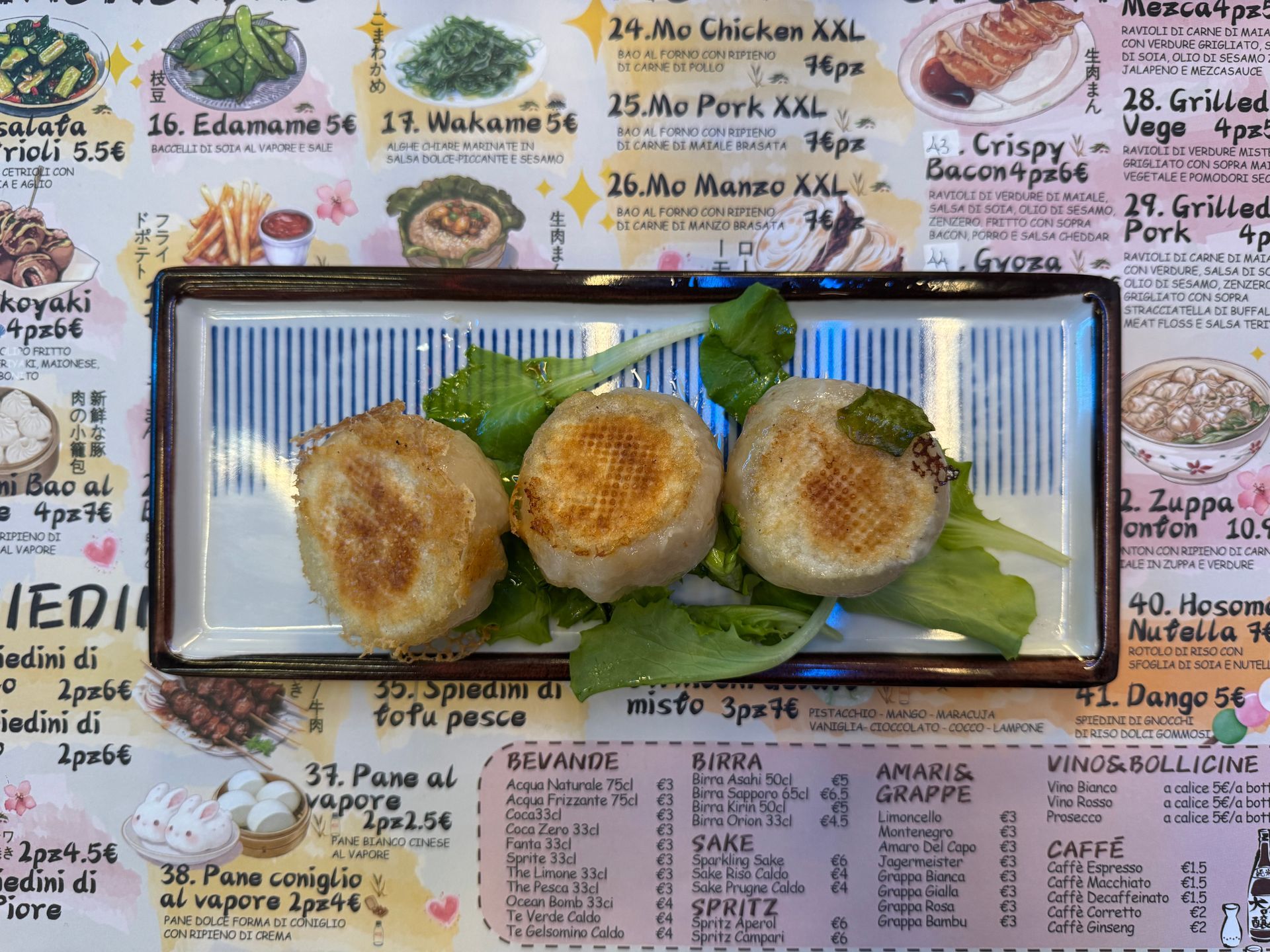 Quattro ravioli dorati fritti su un piatto rettangolare con guarnizione di lattuga, su uno sfondo con menù stampato.