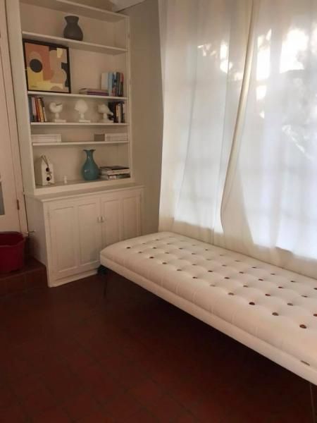 Bright room with white tufted bench, curtained window, and built-in shelf with decor
