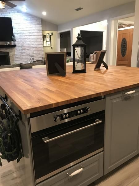 Kitchen island with wooden countertop, built-in oven, and decorative lanterns in a modern home interior