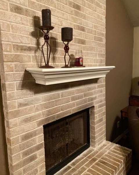 Brick fireplace with white mantel and black candle holders in a living room.