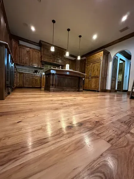 Empty modern kitchen with dark wood cabinets, pendant lights, and glossy hardwood floors
