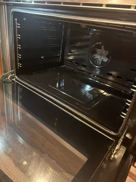 Open oven with glossy black interior and a visible fan at the back