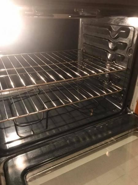 Empty oven interior with metal racks and a bright light on the left side