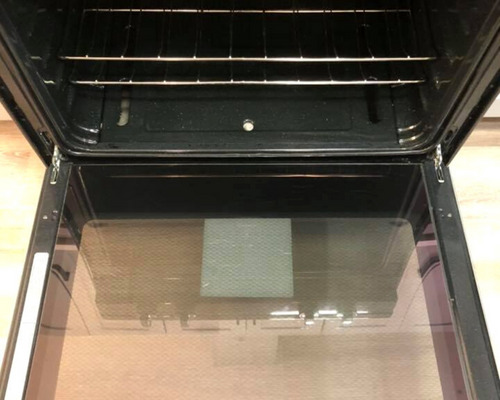 Open oven door with black racks and a reflective glass panel