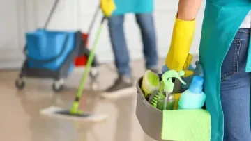 Cleaning staff mopping a floor with supplies in a janitor’s caddy and cart.