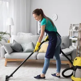 Vacuuming a white rug in a bright living room with a yellow canister vacuum