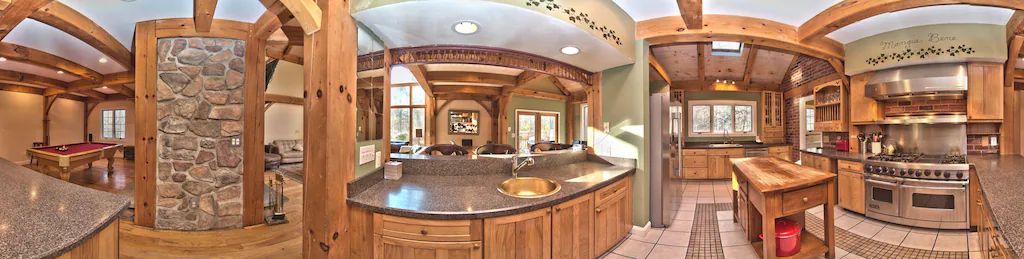 A panoramic view of a kitchen with wooden cabinets and granite counter tops.