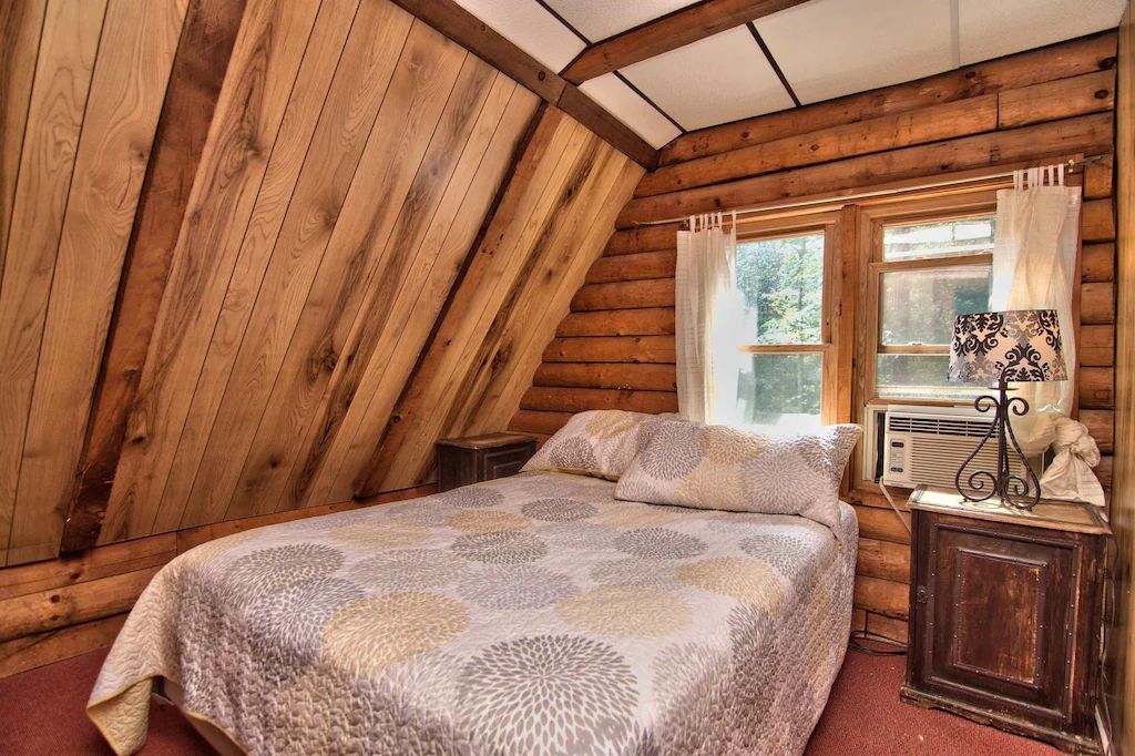 A bedroom in a log cabin with a bed and a window