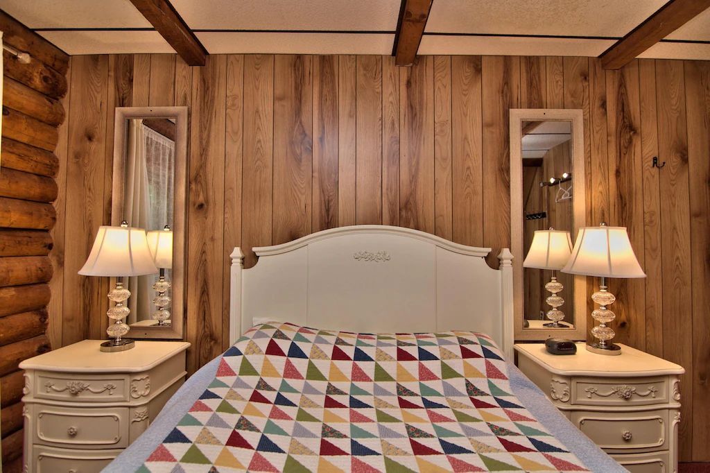 A bedroom with a bed , two nightstands , two mirrors and two lamps.