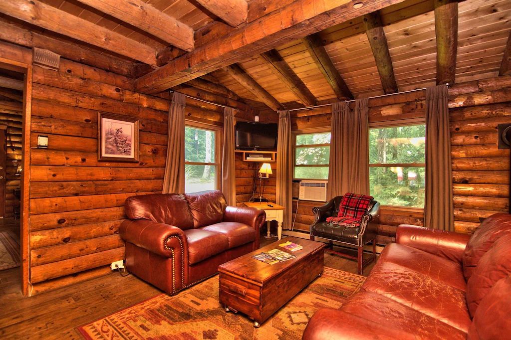 A living room in a log cabin with a couch , chair and coffee table.