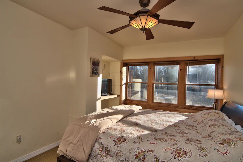 A bedroom with a large bed and a ceiling fan