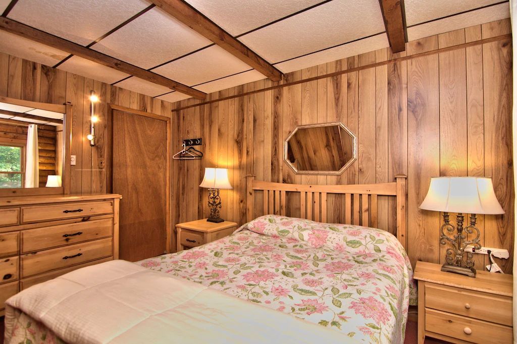 A bedroom with a bed , dresser , nightstand and mirror.