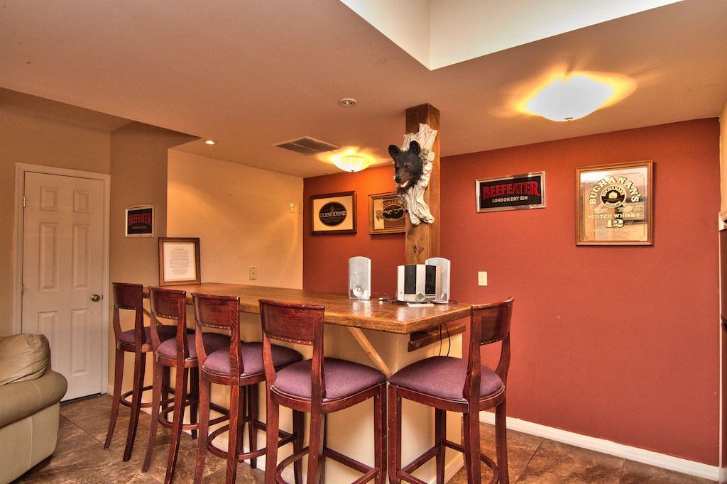 A living room with a bar and stools and a clock on the wall that says 10:08