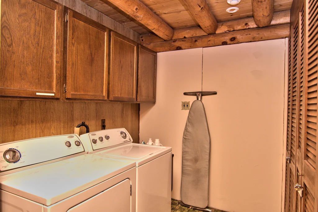 A laundry room with a washer and dryer and an ironing board.