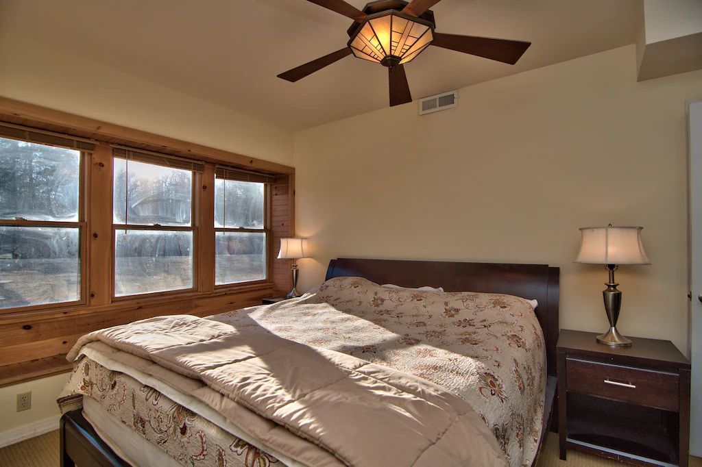 A bedroom with a large bed and a ceiling fan