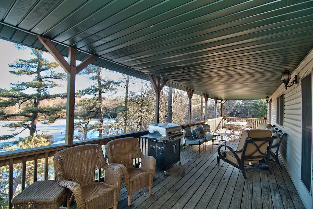 A large screened in porch with wicker furniture and a grill.