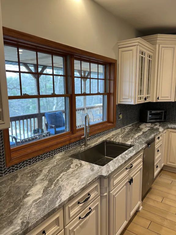 A kitchen with a sink , cabinets , and a window.