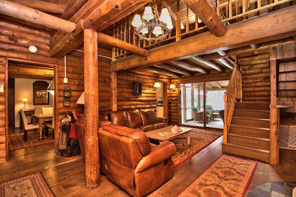 A living room in a log cabin with a couch and stairs.