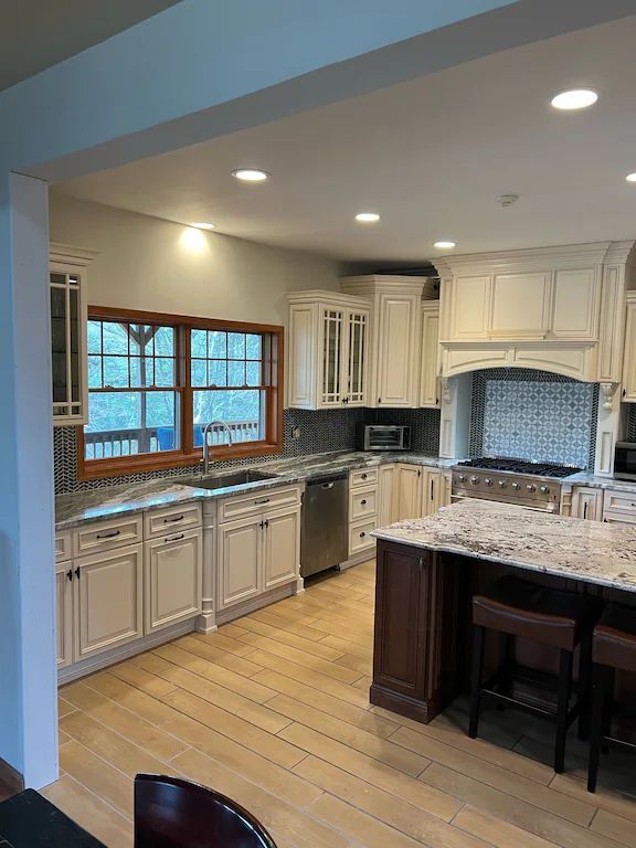 A kitchen with white cabinets , granite counter tops , stainless steel appliances , and a large island.