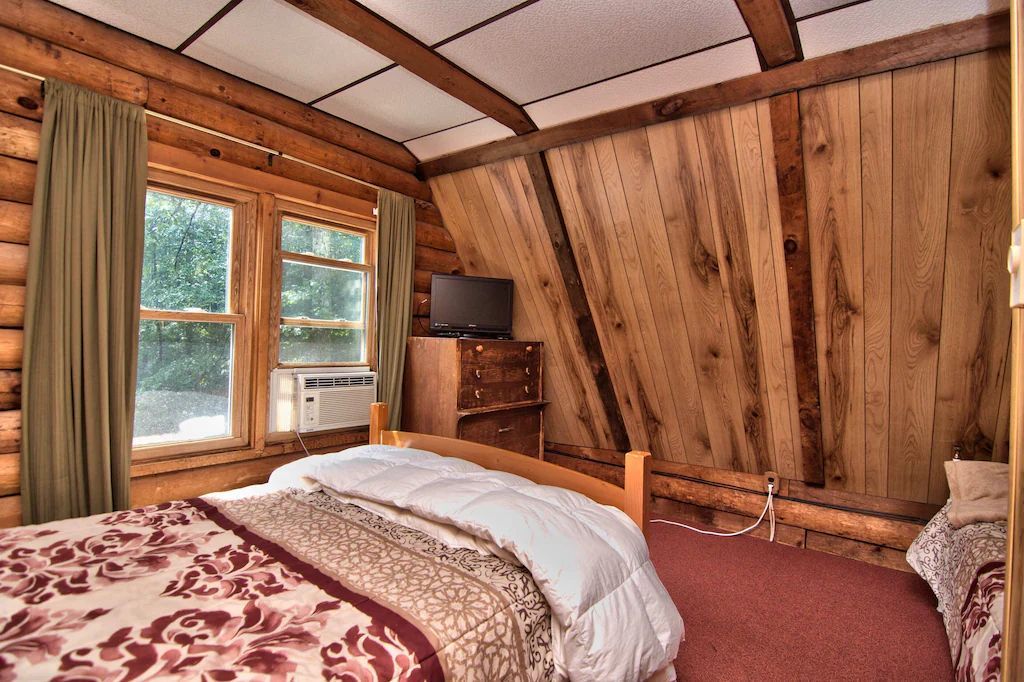 A bedroom in a log cabin with a bed and a television