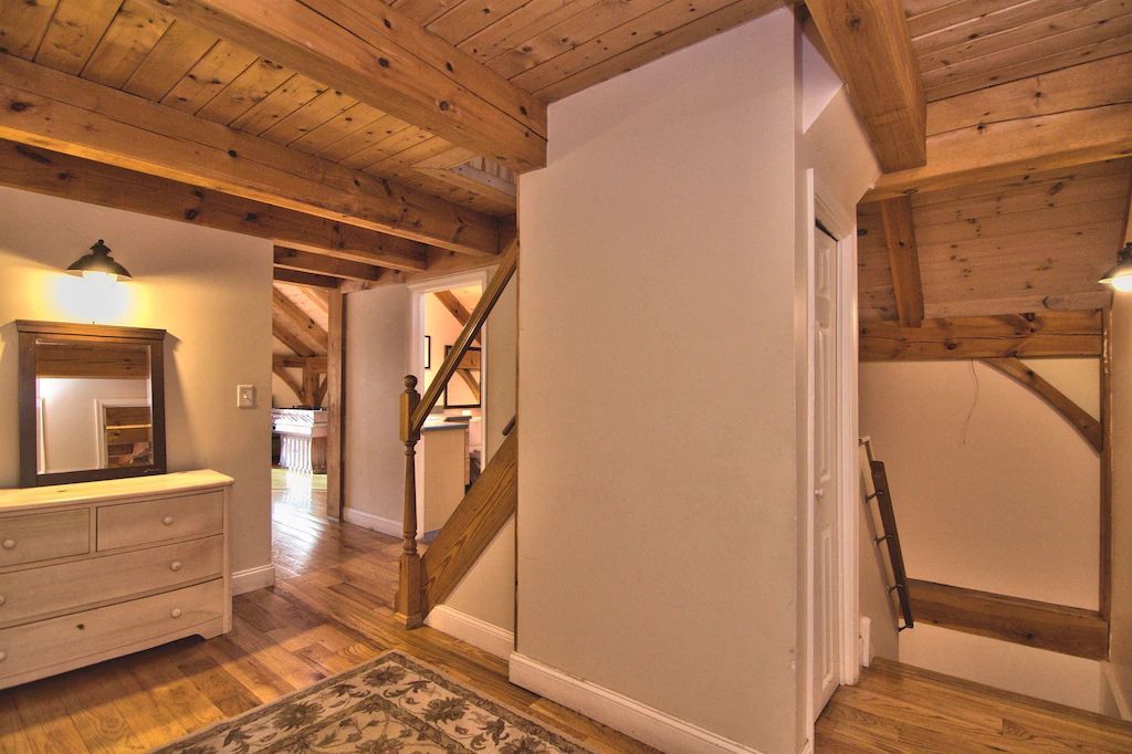 A hallway in a house with wooden beams and a staircase.