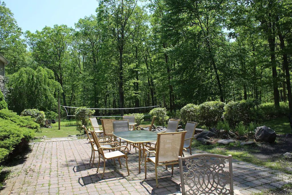 A patio with a table and chairs in the middle of a forest.