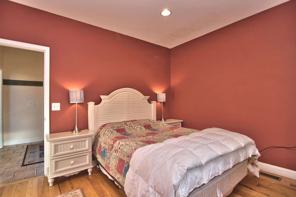 A bedroom with red walls and a king size bed